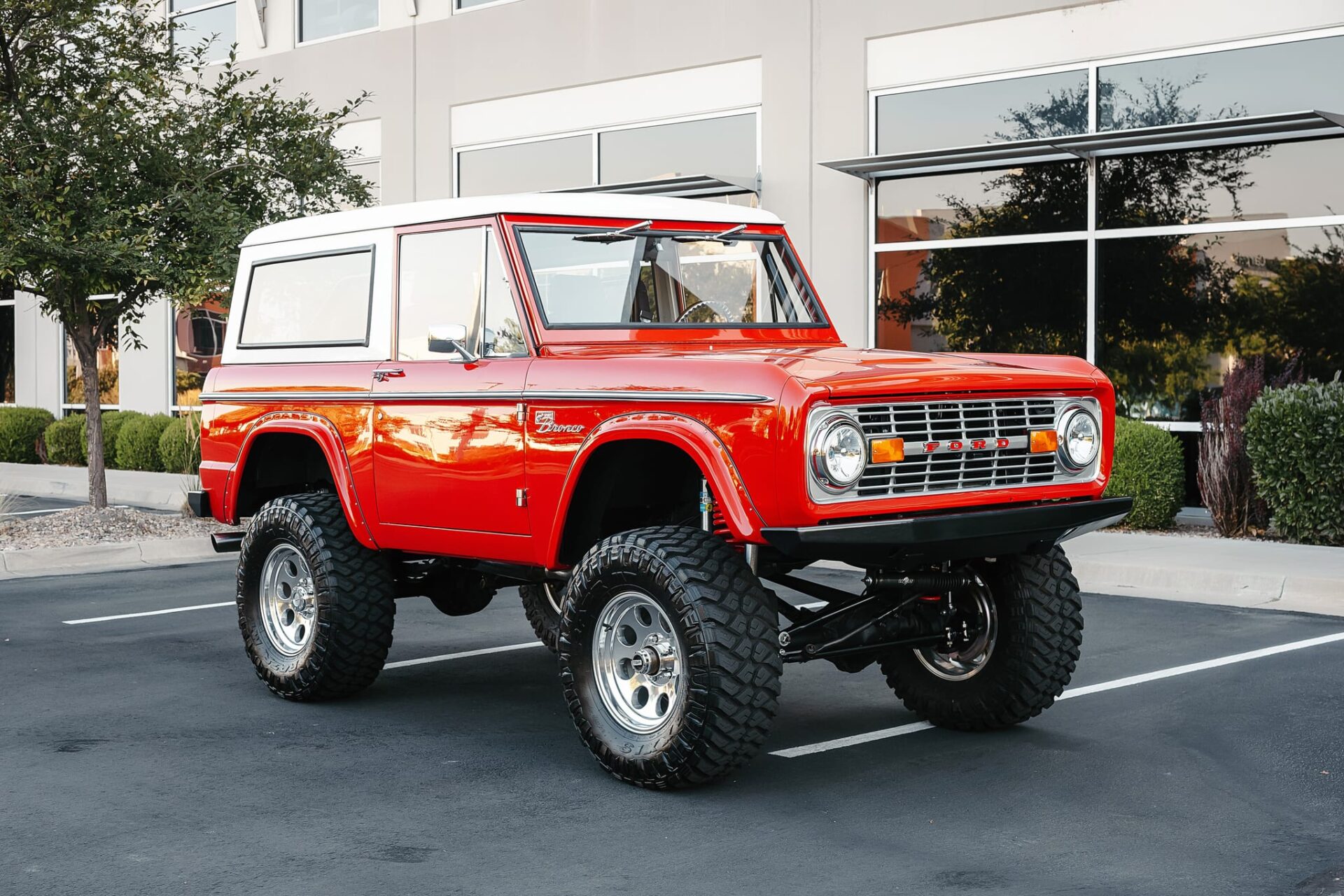 Roter 1968 Ford Bronco mit weißem Hardtop und grobstolligen Reifen