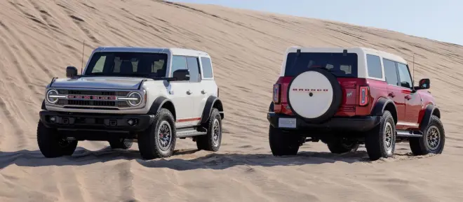 Zwei Ford Bronco Outer Banks 60th Anniversary in Front- und Heckansicht vor einer Sanddüne