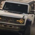 Weißer Ford Bronco Raptor fährt durch eine dichte Staubwolke