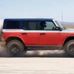 Rot-weißer Ford Bronco Stroppe Edition fährt mit aufgewirbeltem Sand über eine Salzfläche