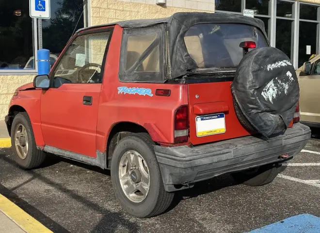 Roter Geo Tracker LSi von 1995 in Heck-Dreiviertelansicht mit außen montiertem Ersatzrad