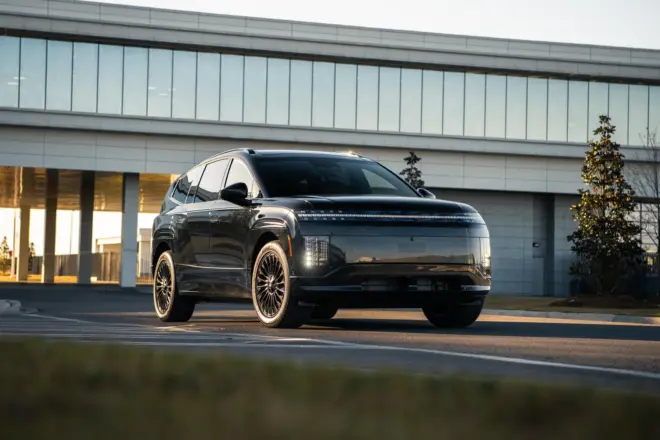 Schwarzer Hyundai Ioniq 9 Calligraphy Black Ink fährt vor einem modernen Gebäude