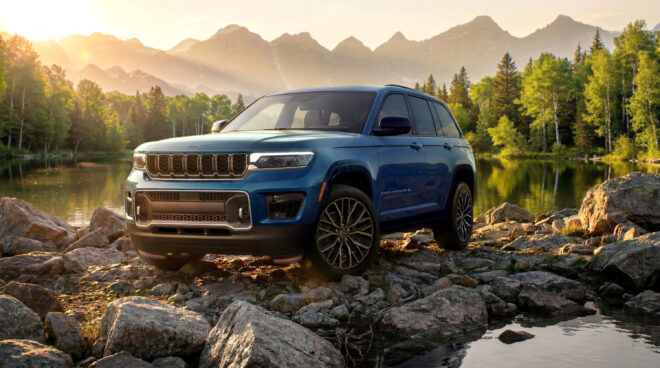 Blauer Jeep Grand Cherokee Overland 2027 in Front-Dreiviertelansicht vor einem Bergsee