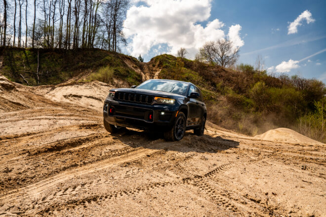 Schwarzer Jeep Grand Cherokee Trailhawk 2027 beim Anstieg auf einem sandigen Offroad-Hügel