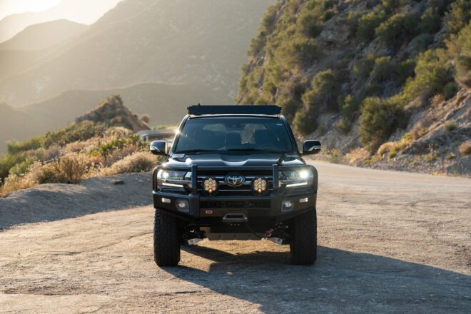 Schwarzer 2021 Toyota Land Cruiser Heritage Edition mit ARB-Stoßfänger, Seilwinde und Zusatzscheinwerfern vor einer Bergkulisse