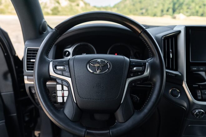 Lenkrad, Kombiinstrument und Zusatzschalter im Fahrerbereich des schwarzen Toyota Land Cruiser Heritage Edition