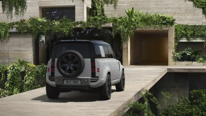 Weißer Land Rover Defender Vertex 110 in Heck-Dreiviertelansicht mit außen montiertem Ersatzrad