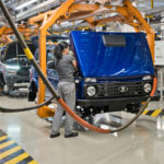 Arbeiter bei Karosseriearbeiten an einem blauen Lada Niva Legend