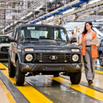 Mitarbeiterin neben einem grauen Lada Niva Legend auf dem Werksband