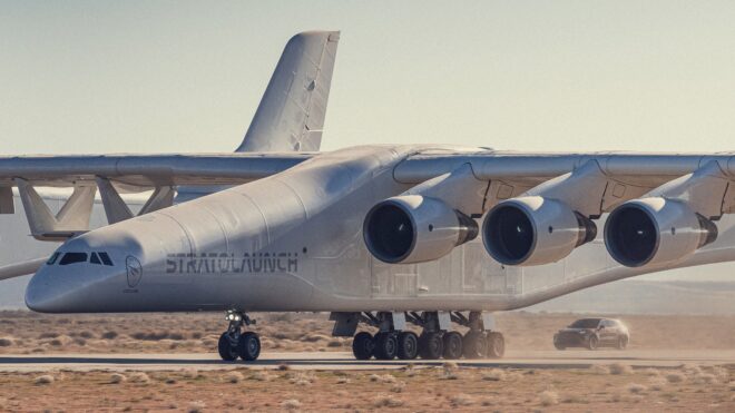 Stratolaunch Roc rollt mit einem Porsche Cayenne Turbo Electric auf der Landebahn