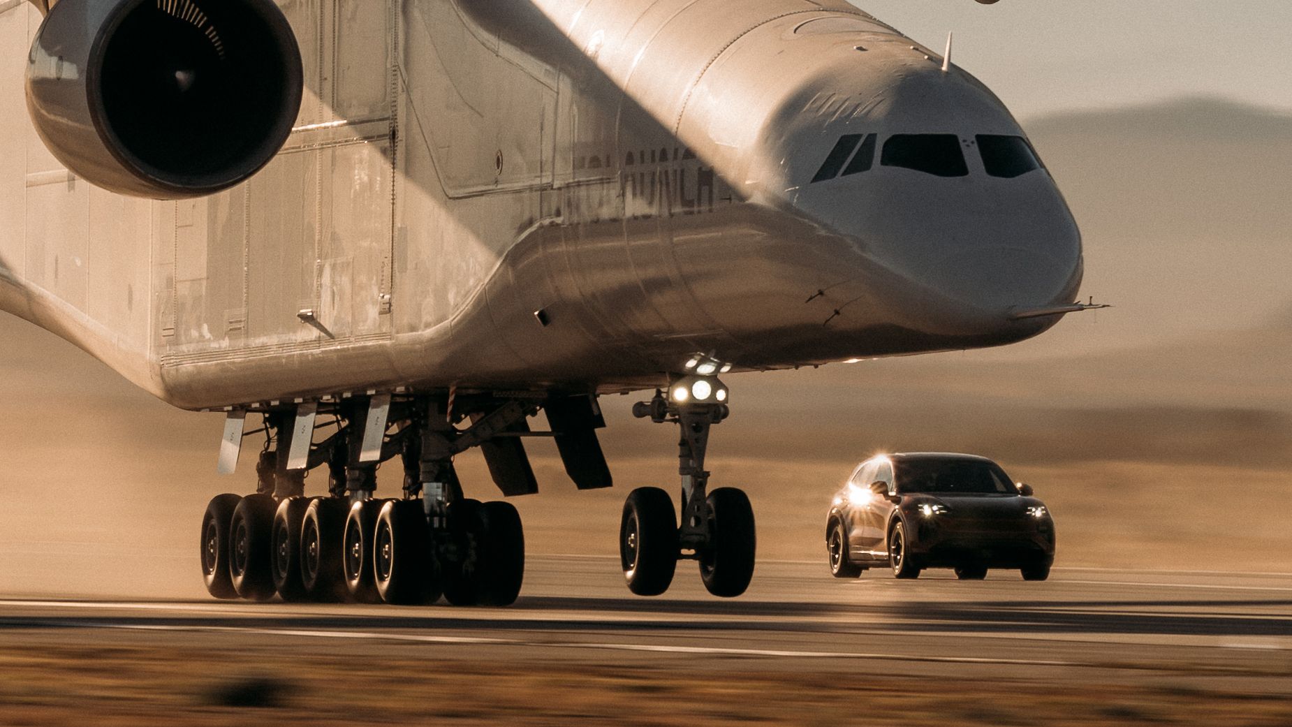 Porsche Cayenne Turbo Electric neben dem Fahrwerk des Stratolaunch Roc